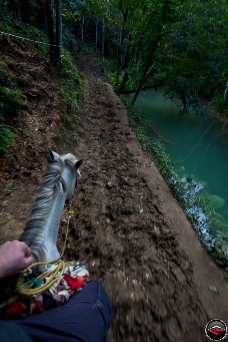 horseback riding on a narrow muddy path next to a caribbean stream Cascada El Limon Dominican Republic