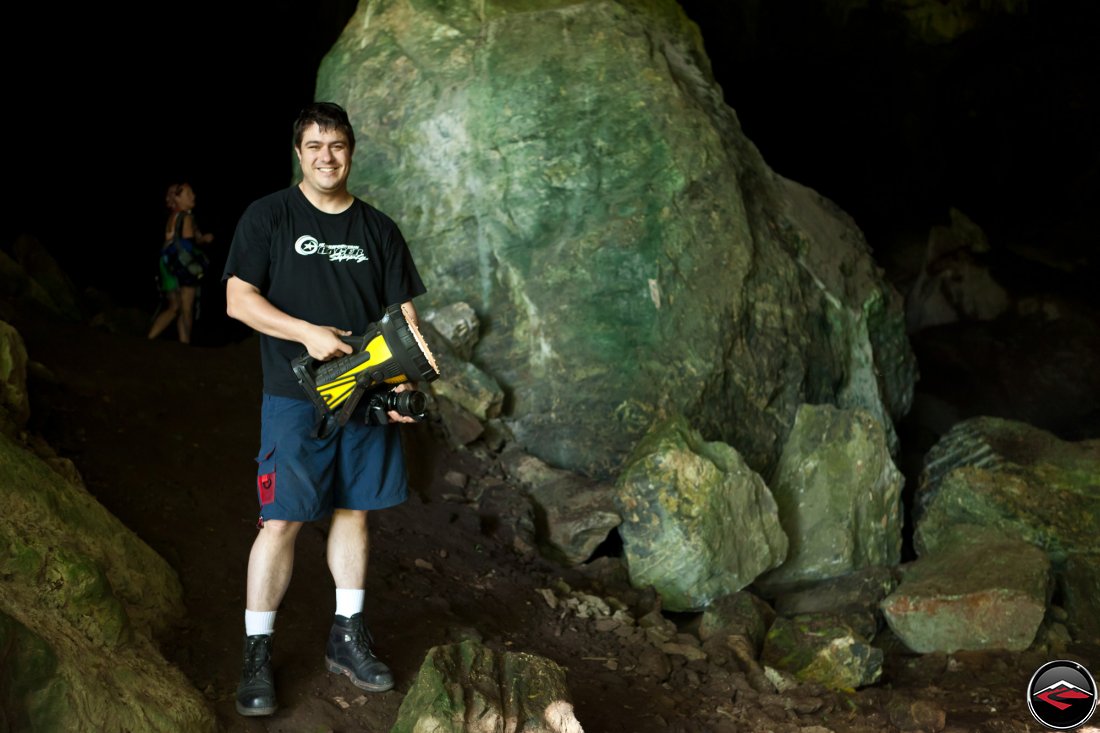 Man standing in a cave holding an extremely large flashlight