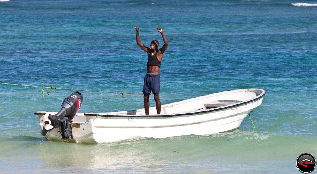 grateful dominican republic man standing in a boat on the caribbean ocean