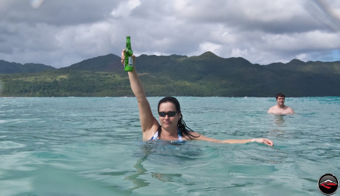 woman holding a presidente Beer in the air while she stands in the water Playa Rincon Dominican Republic