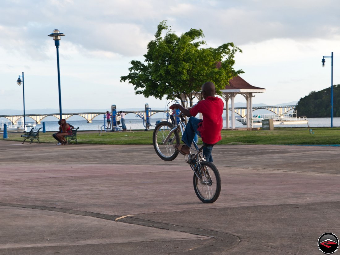 local boy from the dominican republic rides a wheelie on his bicycle for tips