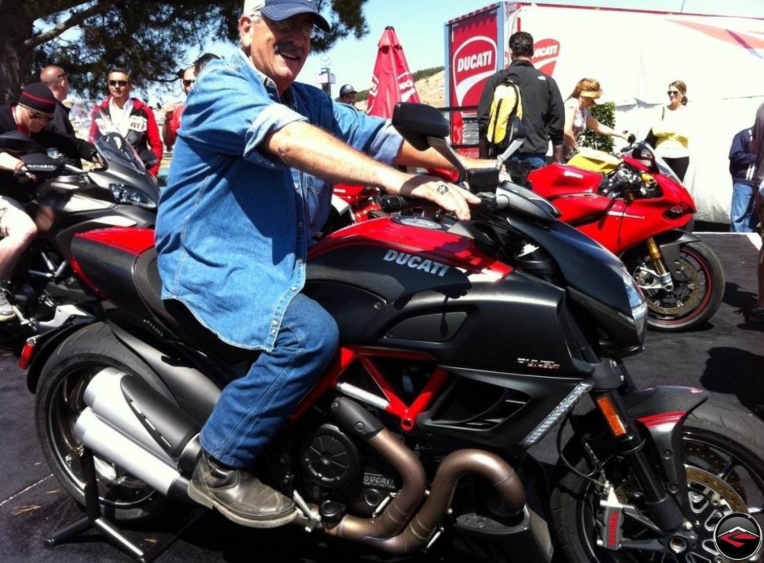 Tom sitting on a Ducati Diavel Black Carbon at Mazda Laguna Seca Raceway, during the 2012 MotoGP races