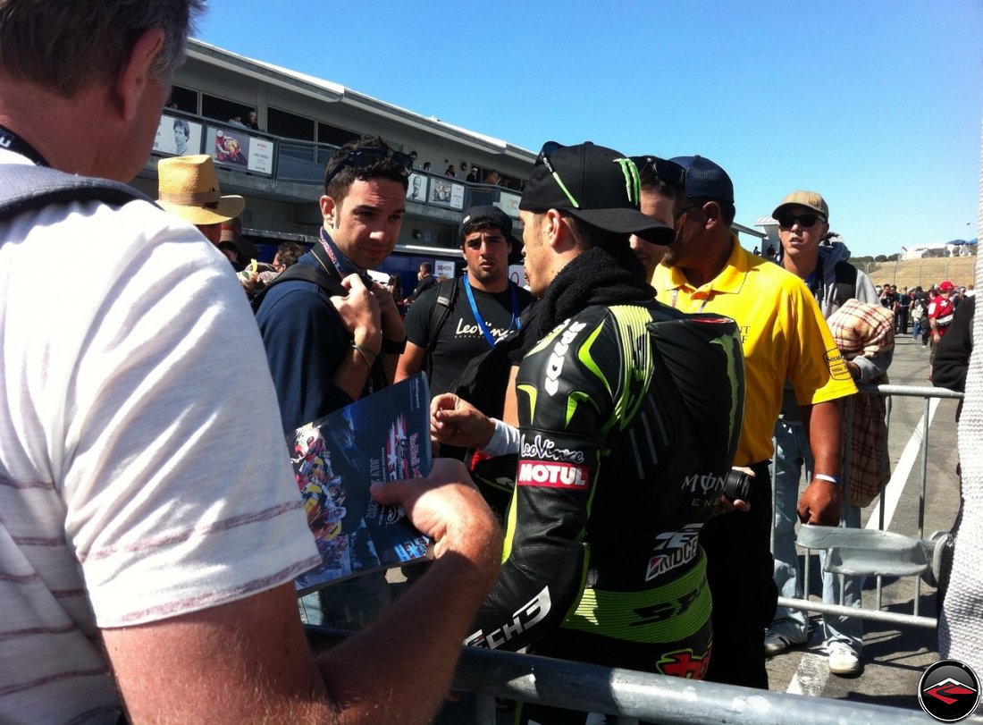 2012 MotoGP Tech 3 Racer Andrea Dovizioso, wearing Green Spidi Leathers, signing autographs at Laguna Seca raceway